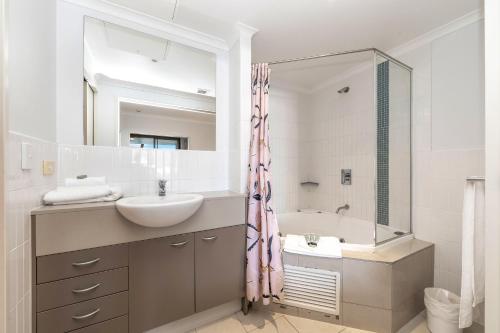 a bathroom with a sink and a tub and a mirror at Ettalong Beach Luxury Apartments in Ettalong Beach