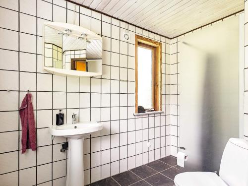 a white tiled bathroom with a sink and a mirror at 6 person holiday home in Øster Assels in Øster Assels