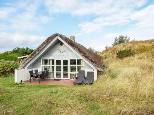 a thatch roof house with a deck and chairs at 3 person holiday home in Ringkøbing in Ringkøbing