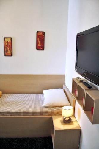 a small room with a bed and a flat screen tv at Rooms Fitea in Osijek