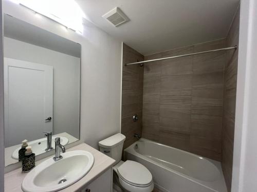 a bathroom with a sink and a toilet and a tub at Stylish 2-Story Condo with Balcony in Kitchener