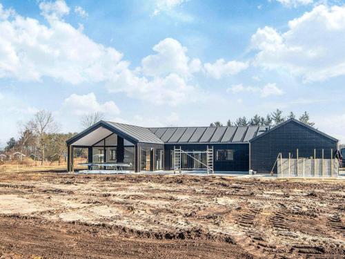 a large black house in a field next to a dirt field at 5 star holiday home in Ansager in Ansager