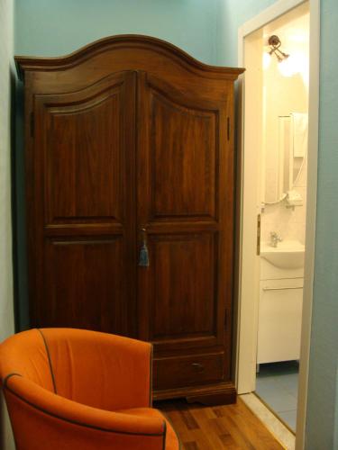 an orange chair and a wooden door in a bathroom at Soggiorno Michelangelo in Florence
