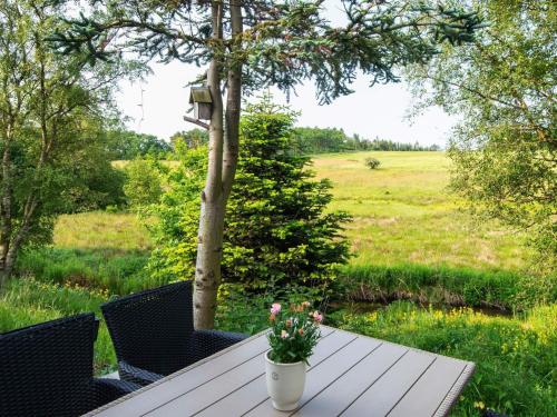 a wooden table with a vase of flowers on it at Tranquil Riverside Retreat in Holstebro