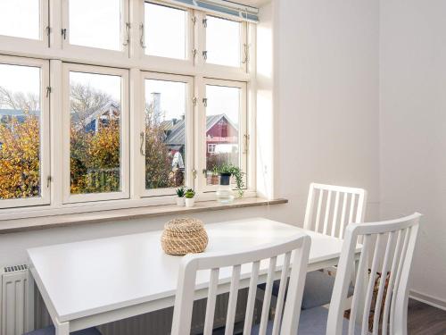 a white table and chairs in a room with windows at Charming Retreat in Ringkobing in Ringkøbing