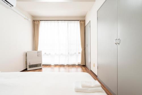 a bedroom with a white bed and a window at Alice in Maruyama 円山公園近く マーケットすぐ in Sapporo