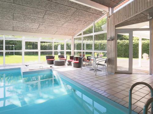 a swimming pool with chairs and a table in a house at 10 person holiday home in Tisvildeleje in Tisvildeleje