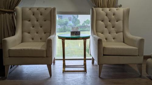 two chairs and a table with a cake on it at Premium Guest House - Pentasquare in Lahore