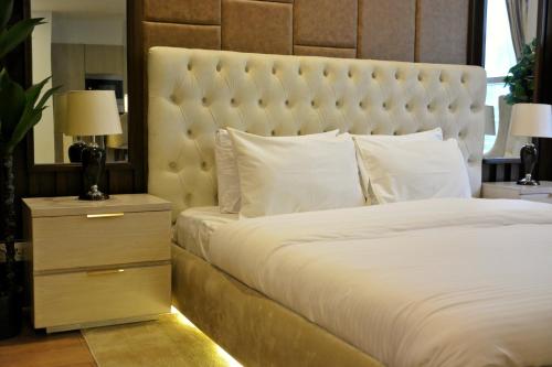 a bedroom with a large white bed and a night stand at Premium Guest House - Pentasquare in Lahore
