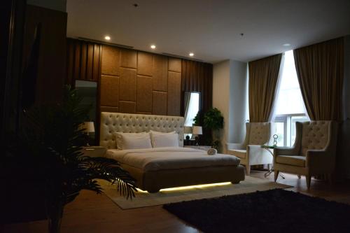 a bedroom with a large bed and two chairs at Premium Guest House - Pentasquare in Lahore