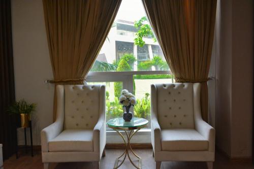two chairs and a table in front of a window at Premium Guest House - Pentasquare in Lahore