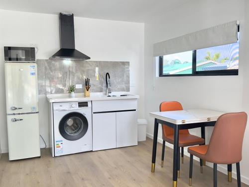 a kitchen with a washing machine and a table with chairs at Amber 1bdr-studio in Daisy Hill in Slacks Creek