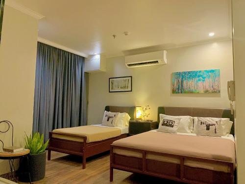 a hotel room with two beds and a window at Hotel Tiffany - Laoag in Laoag
