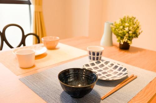 a dining room table with a black bowl and chopsticks at SN2B おしゃれな部屋で家族団欒 大須商店街徒歩10分 8人可 Fashionable room for family gatherings Osu Shopping Street 10 min walk 8 people can stay in Nagoya