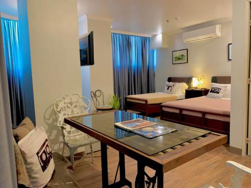 a room with two beds and a table in a room at Hotel Tiffany - Laoag in Laoag