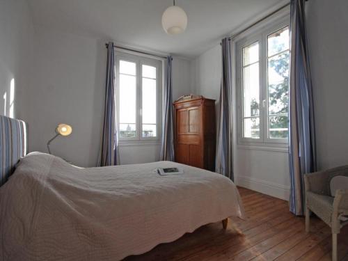 a bedroom with a bed and two windows and a chair at Maison de maître 19ème, parc arboré et cheminée, centre L'Aigle - FR-1-497-57 in LʼAigle