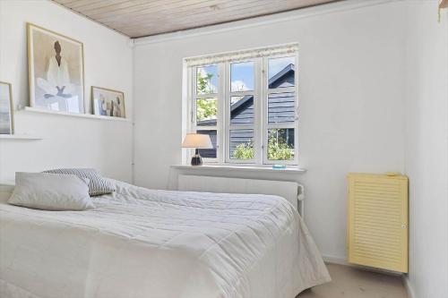 a white bedroom with a bed and a window at TV1673-Bindslev-Noddevaenget-1 in Bindslev