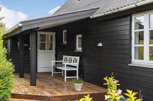 a black house with a white chair on a deck at TV1673-Bindslev-Noddevaenget-1 in Bindslev