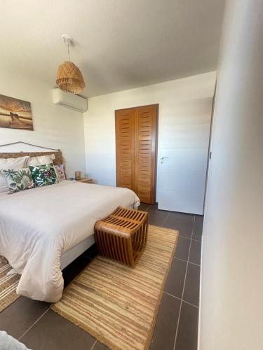 una camera da letto con un letto grande con uno sgabello in rattan di Wave Coconut Villa a Le Moule