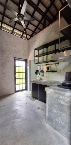 an empty room with a kitchen with a ceiling fan at Lot2990 Seremban 3 Homestay by SkyLimit Suites in Seremban