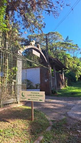 a sign in front of a gate in front of a building at Pousada Luar de Penedo in Penedo