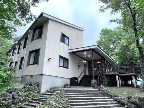 a house with stairs leading up to it at 草津白根 マウンテンビューロッジ in Kusatsu