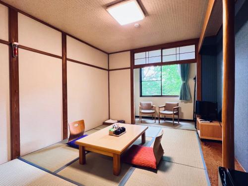 a living room with a table and a tv at 草津白根 マウンテンビューロッジ in Kusatsu
