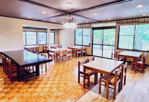 a dining room with tables and chairs and windows at 草津白根 マウンテンビューロッジ in Kusatsu