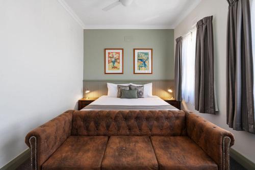 a bedroom with a couch in front of a bed at George Inn Rooms at Royal Tenterfield in Tenterfield
