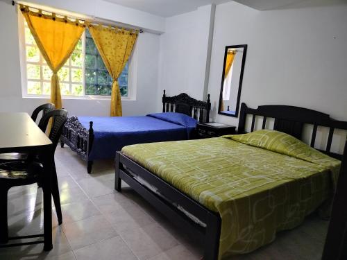 Un dormitorio con dos camas y una mesa y un espejo. en Casita entre árboles, casa de huéspedes céntrica y cómoda en San Fernando, Cali, en Cali