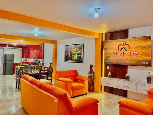 a living room with orange furniture and a restaurant at Mi bello Zacatlán-Suite Manzana Delicia in Zacatlán