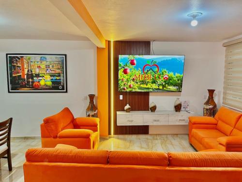 a living room with orange furniture and a flat screen tv at Mi bello Zacatlán-Suite Manzana Delicia in Zacatlán