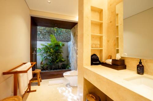 a bathroom with a sink and a toilet and a window at Amarta Beach Retreat by Nakula in Tabanan