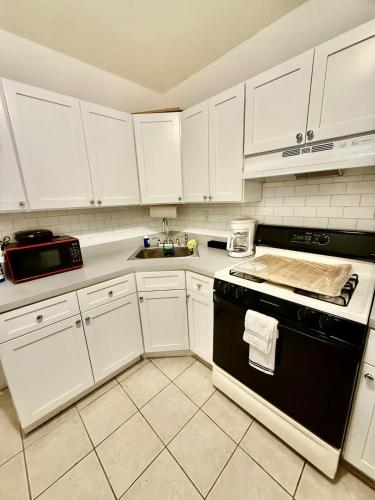 a kitchen with white cabinets and a black stove top oven at NYCRiverside 2BR Apt 20MintsTime Square in West New York