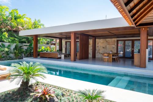an outdoor living area with a swimming pool and a house at Amarta Beach Retreat by Nakula in Tabanan
