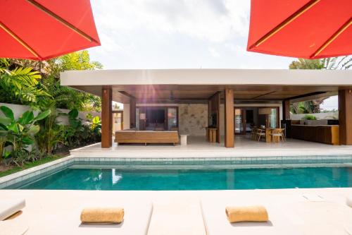 a villa with a swimming pool and a house at Amarta Beach Retreat by Nakula in Tabanan