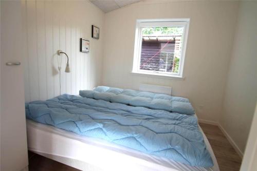 Una cama con un edredón azul en un dormitorio. en K19088-Eskebjerg-Bjarnesvej-10, en Eskebjerg