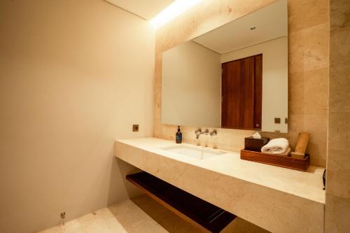 a bathroom with a sink and a mirror at Amarta Beach Retreat by Nakula in Tabanan