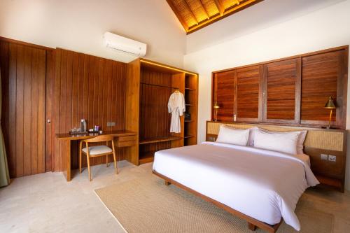 a bedroom with a large white bed and a desk at Amarta Beach Retreat by Nakula in Tabanan