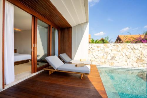 a villa with a swimming pool and a lounge chair at Amarta Beach Retreat by Nakula in Tabanan