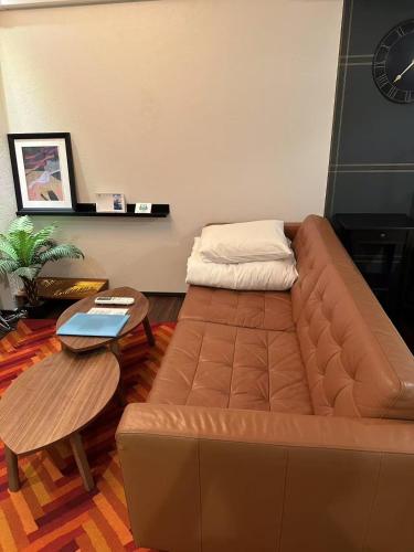a living room with a brown couch and a table at Tsubame Hotel Asakusabashi 3 minutes walk from Asakusabashi Station Near Asakusa, Akihabara, and Ueno Cooking utensils and kitchen washing machine available Direct access to Haneda and Narita airports in Tokyo