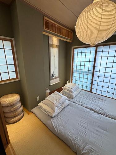 a bedroom with a bed with white pillows and windows at Tsubame Hotel Asakusabashi 3 minutes walk from Asakusabashi Station Near Asakusa, Akihabara, and Ueno Cooking utensils and kitchen washing machine available Direct access to Haneda and Narita airports in Tokyo