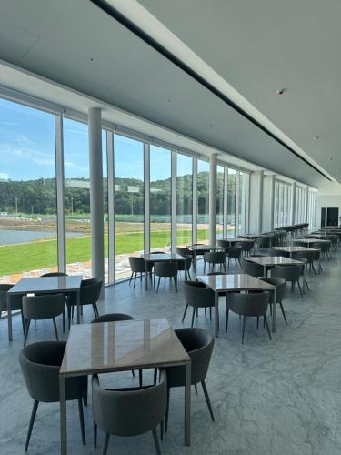a dining room with tables and chairs and windows at Uniisland The Spaville in Incheon