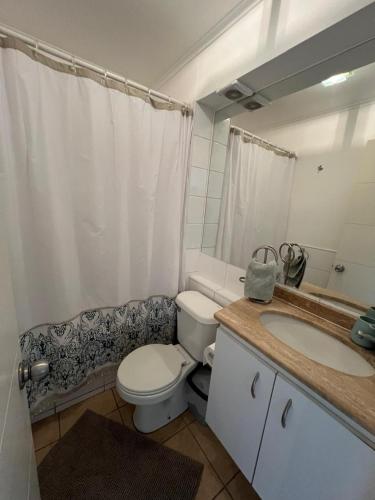 a bathroom with a toilet and a sink and a mirror at Avenida del Mar Condominio Oceanic in La Serena