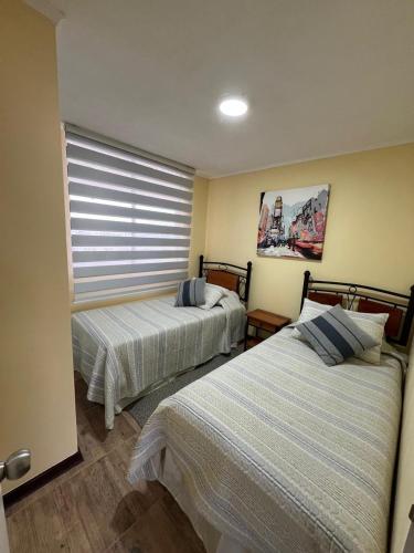 two beds sitting in a room with a window at Avenida del Mar Condominio Oceanic in La Serena