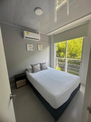 a bedroom with a white bed and a window at Disfruta y descansa en esta casa con Aire acondicionado in Ricaurte