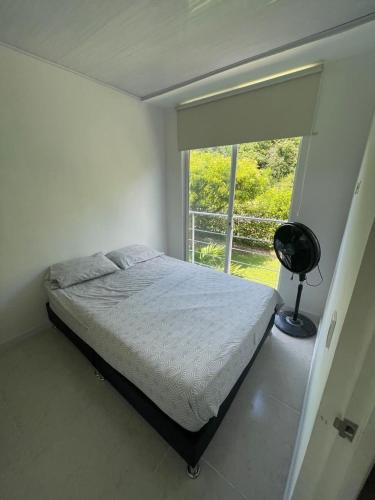 a white bedroom with a bed and a window at Disfruta y descansa en esta casa con Aire acondicionado in Ricaurte