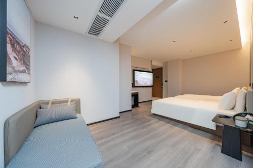 a bedroom with a bed and a flat screen tv at Atour Hotel Guangzhou Pazhou Exhibition Center Information Port-Free shuttle bus to Canton Fair in Guangzhou