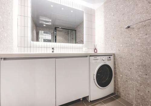 a washing machine in a bathroom with a mirror at Elmomento Songdo in Busan