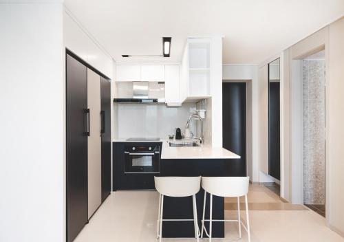 a kitchen with black and white counters and white appliances at Elmomento Songdo in Busan